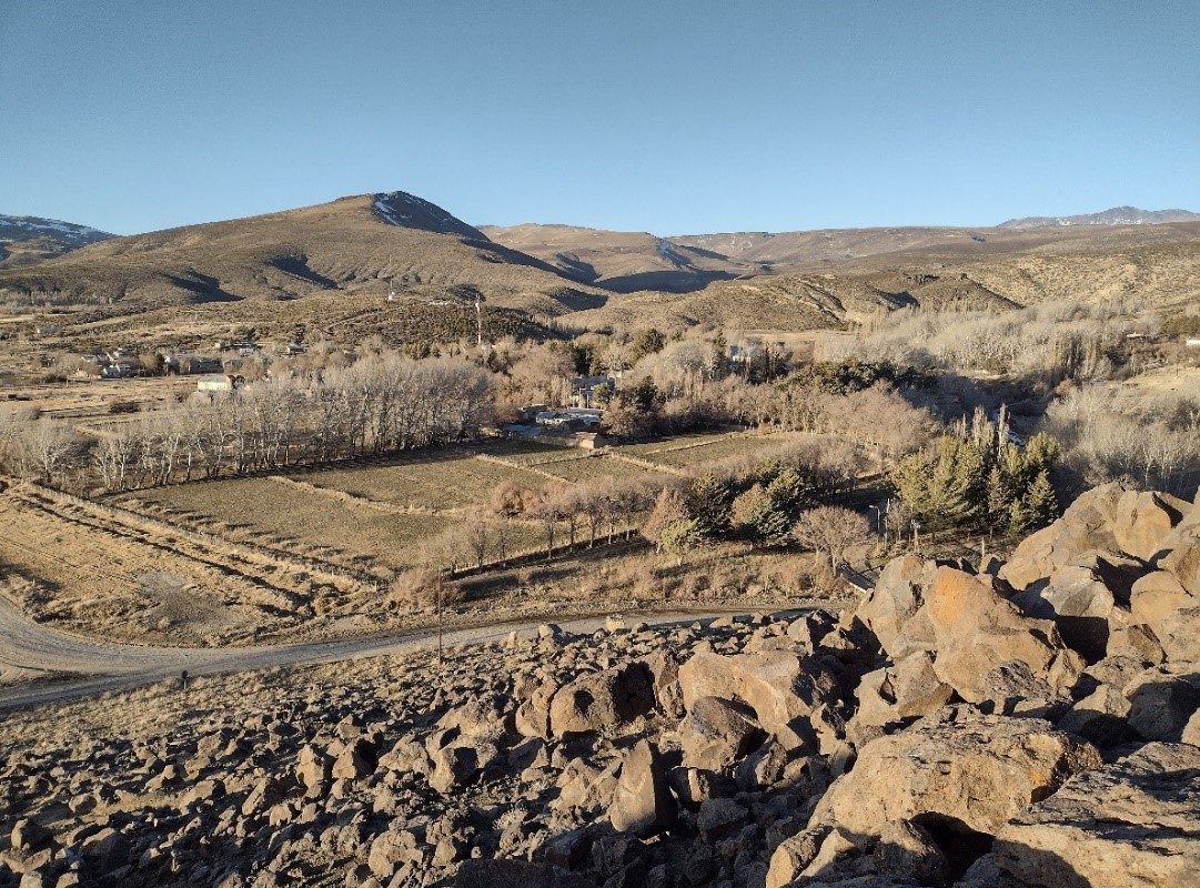 Canal de riego revestido en hormigón entre chacras, con la cordillera de fondo