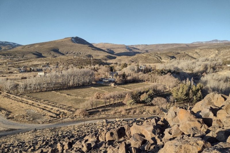 Canal de riego revestido en hormigón entre chacras, con la cordillera de fondo